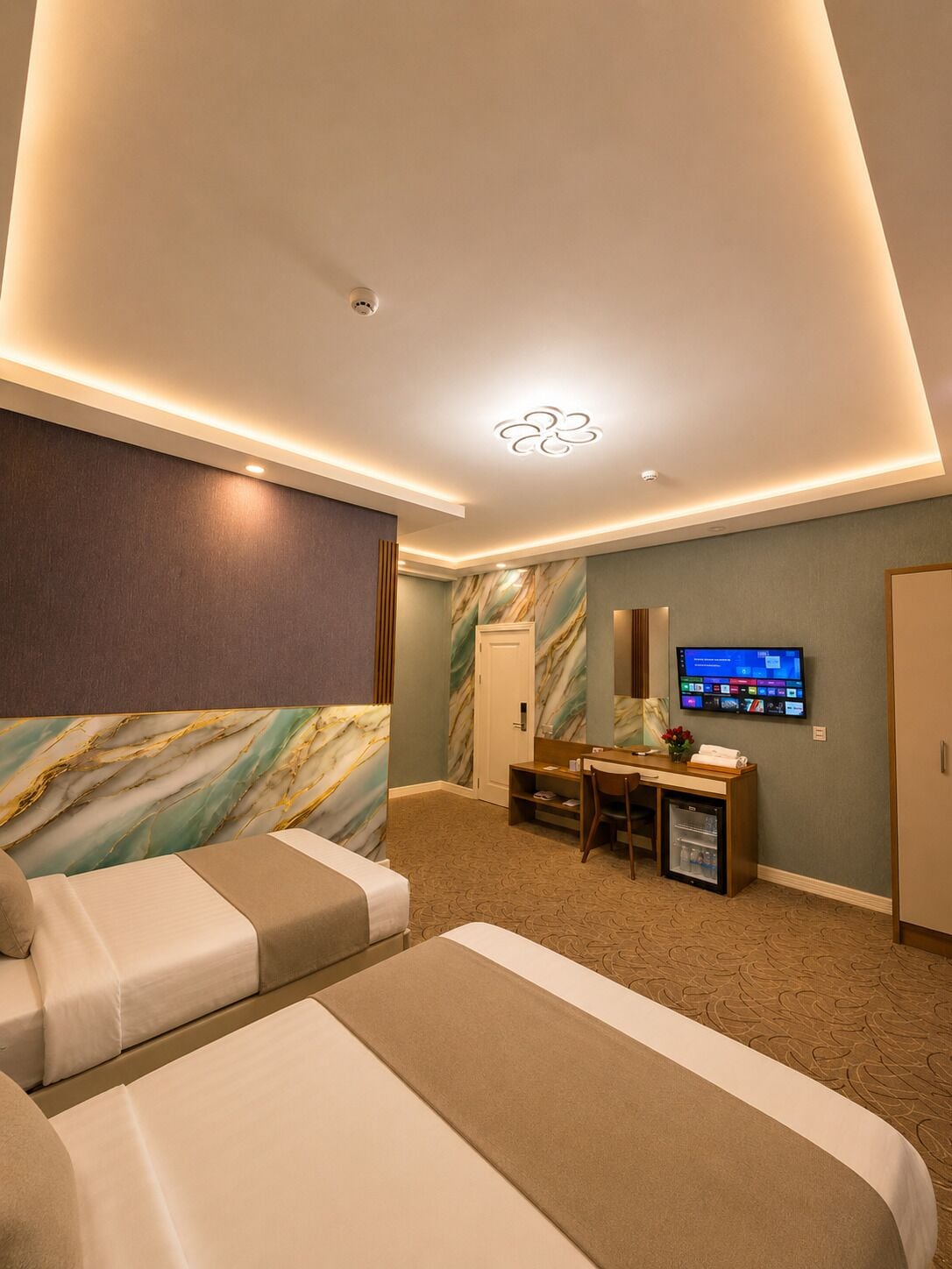Habitación de hotel con cama, escritorio con computadora, televisor y minibar.