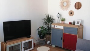 A living room with a TV, wooden cabinets, a sofa, and decorative items. - Maison de Ville à Laleu - La Rochelle (La Rochelle)