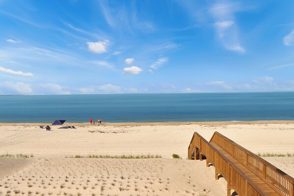 Une plage avec une promenade en bois qui mène à un bâtiment.