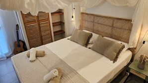 A neatly made bed with pillows, a guitar, and a bedside table with a lamp. - O'Filao (Grand-Bourg)