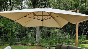 An outdoor deck with a wooden table, two chairs, a sofa, and a large umbrella. - O'Filao (Grand-Bourg)