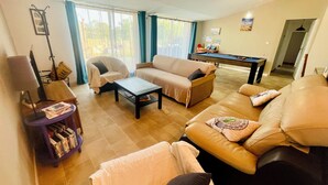 Una sala de estar con sofá, sillón, mesa de centro y mesa de billar.