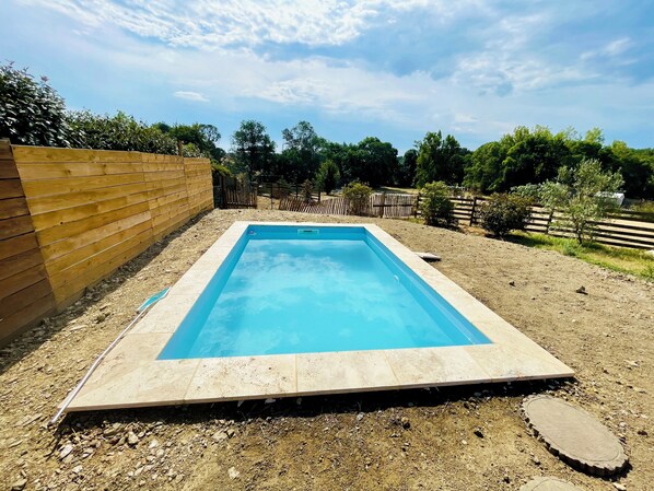 A rectangular swimming pool with a wooden deck surrounding it.