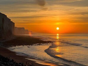 A sunset over a coastal landscape with cliffs and a beach.