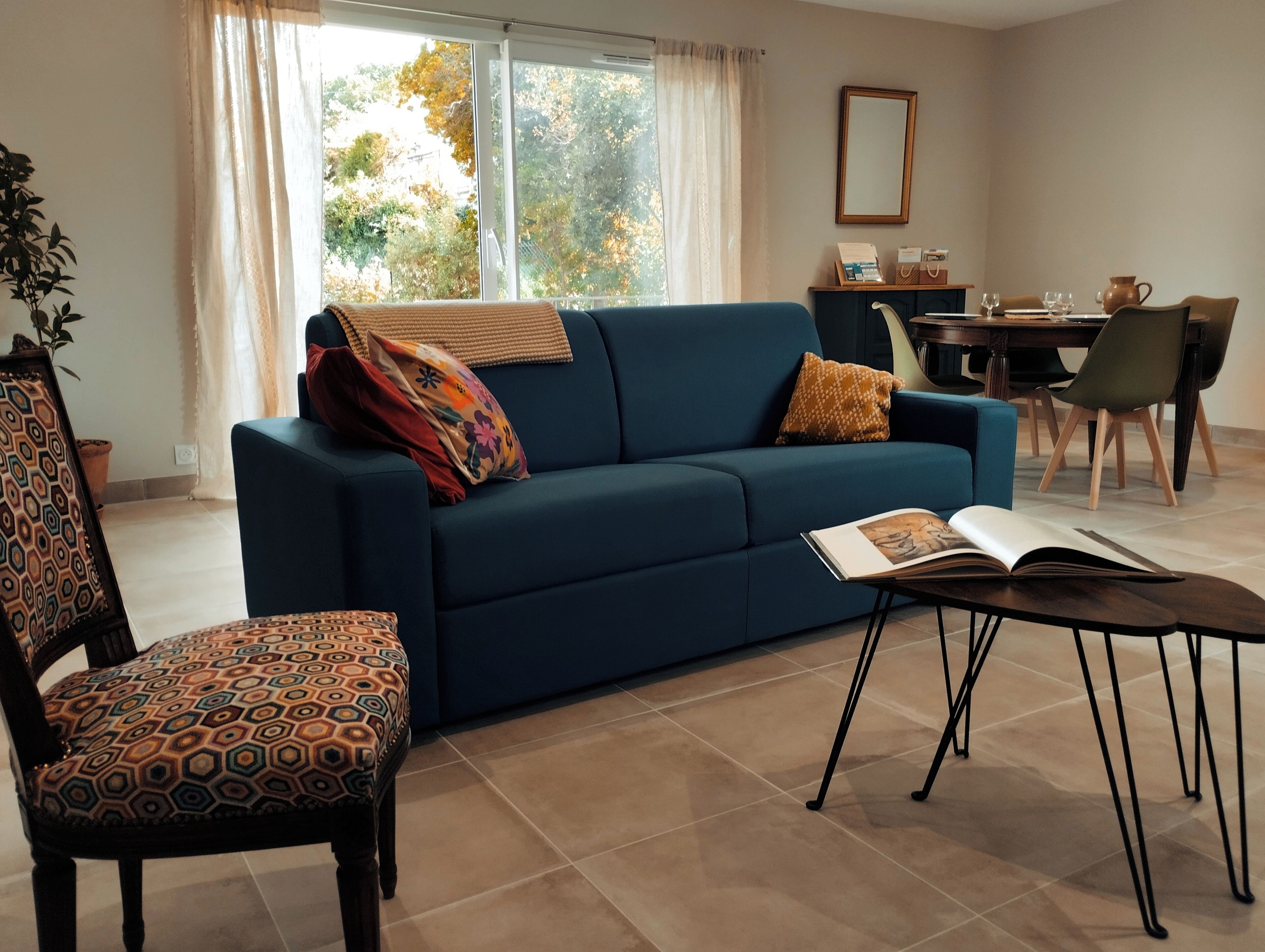 Una sala de estar con un sofá azul, un sillón estampado y una mesa de centro con una revista.