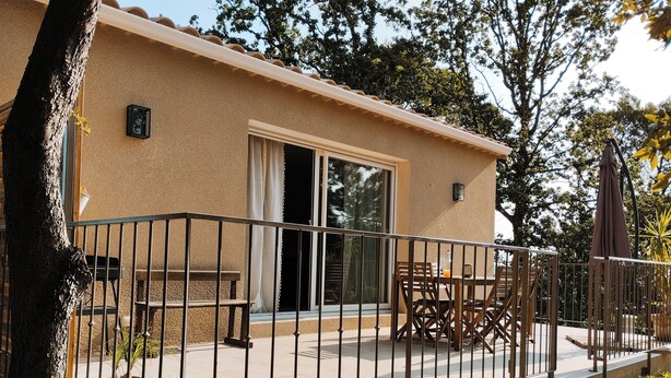 A building with a balcony, a table, and chairs. - Nouveau Maison Avec Jardin aux Portes des Gorges de L'ardèche (Saint-Julien-de-Peyrolas)