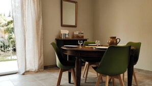 A dining area with a wooden table, green chairs, and a vase. - Nouveau Maison Avec Jardin aux Portes des Gorges de L'ardèche (Saint-Julien-de-Peyrolas)