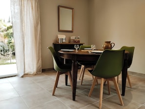 A dining area with a wooden table, green chairs, and a vase.