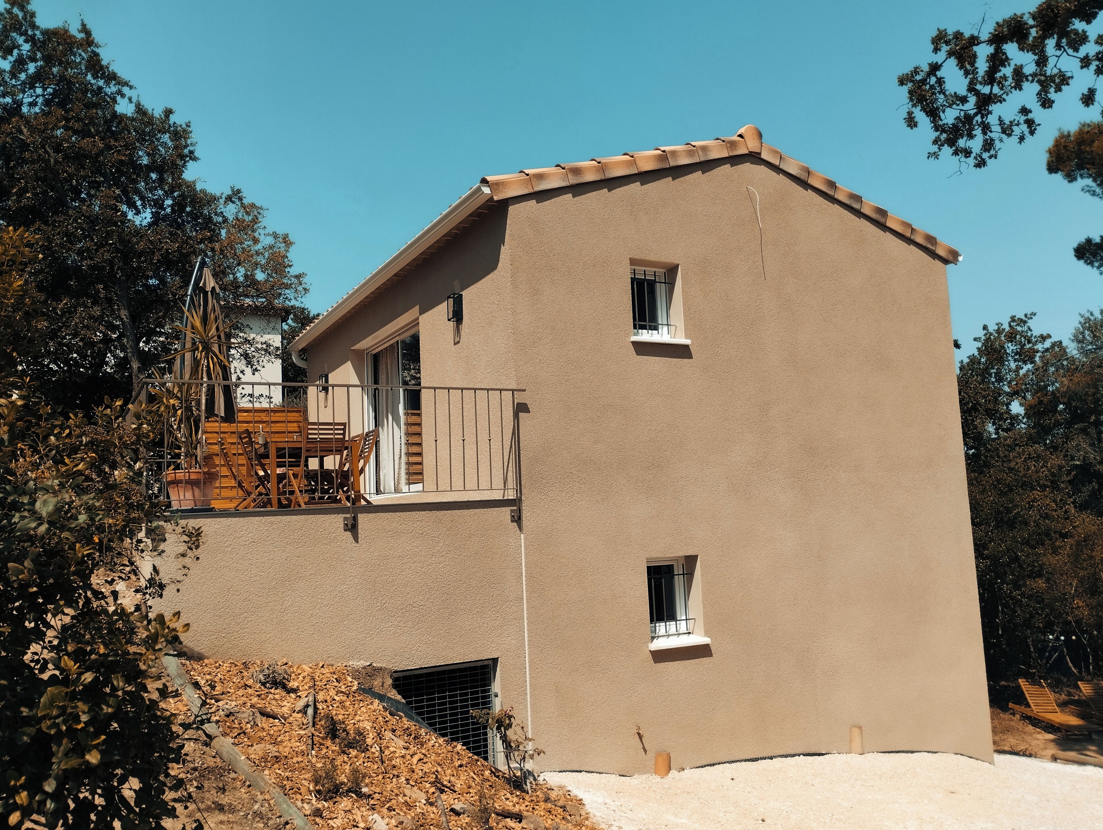A two-story building with a balcony, a small window, and a door.