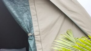 A tent-like structure with a light-colored interior, a blue curtain, and a potted palm plant. - Maasai Hostel Tanzania (Arusha)