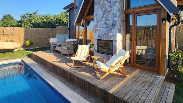 A modern house with a stone fireplace, a swimming pool, and outdoor seating. - Mayan Bungalows (Sapanca)