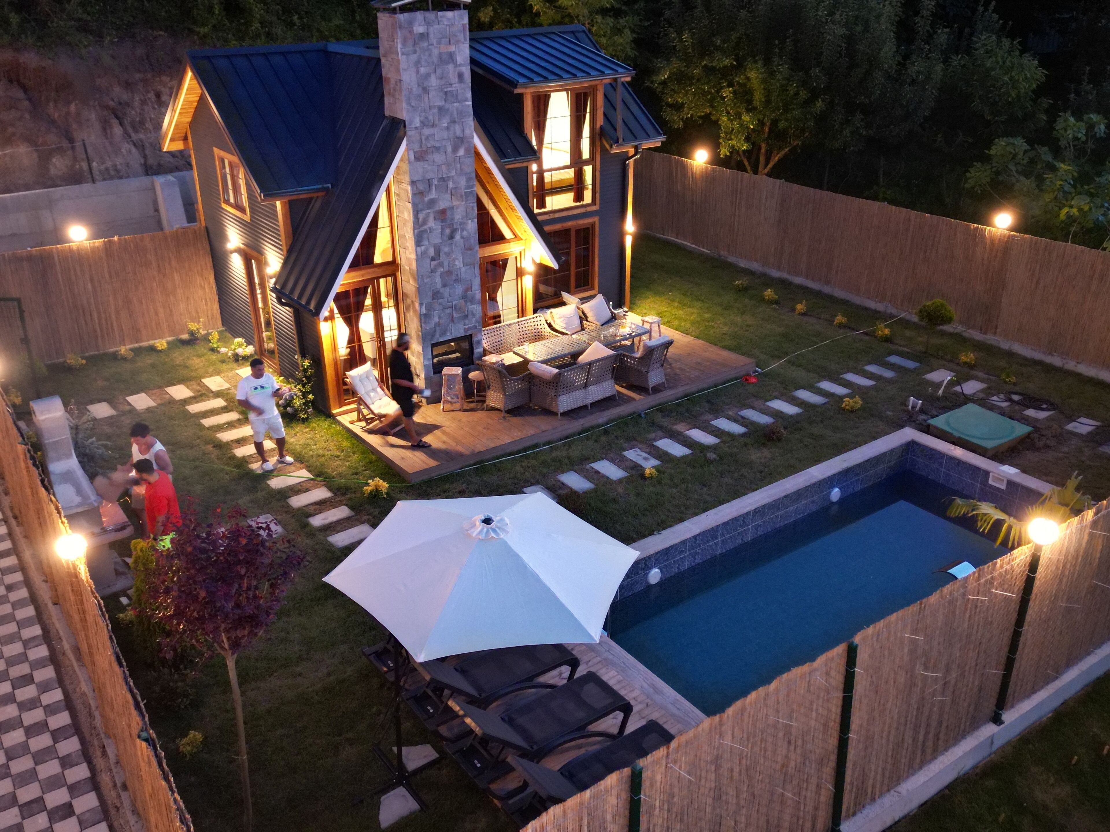 A modern house with a stone fireplace, outdoor seating, and a swimming pool.