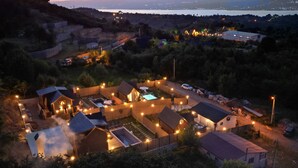 An aerial view of a residential area with multiple houses, a swimming pool, and a clear view of a distant body of water. - Mayan Bungalows (Sapanca)