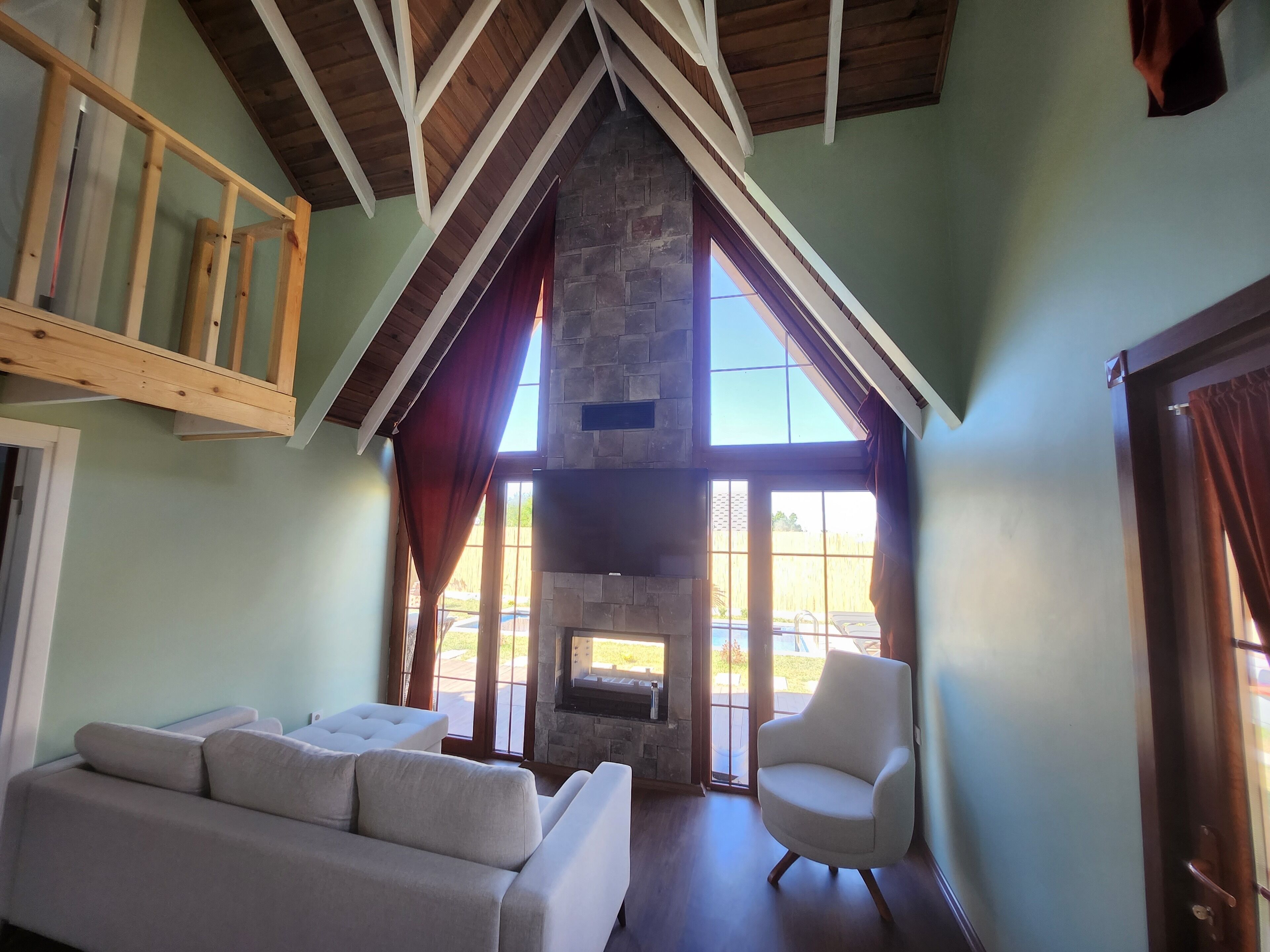 Una sala de estar con chimenea de piedra, un sofá blanco y estructura de techo de madera.