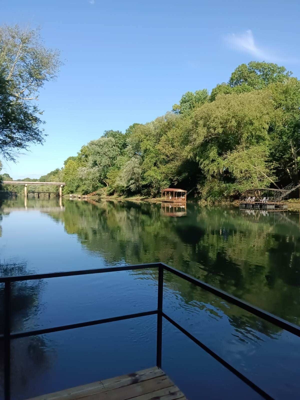 Une rivière paisible, avec un quai en bois et un kiosque.