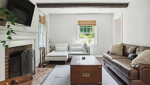 A living room with a fireplace, a television mounted on the wall, a brown leather sofa, a white sofa, and a wooden coffee table. - Large yard - Quiet area - 15 min to DC (Falls Church)