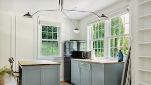 A kitchen with a central island, a stove, a microwave, and a sink. There are two windows with white frames and a view of greenery outside. - Large yard - Quiet area - 15 min to DC (Falls Church)