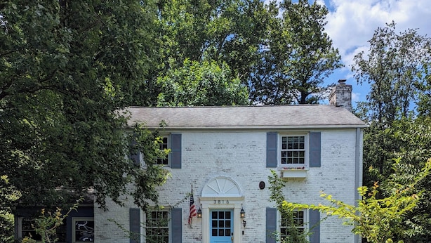 A white brick house with a blue door and shutters, surrounded by a gravel pathway and potted plants. - Large yard - Quiet area - 15 min to DC (Falls Church)