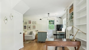 A modern kitchen with a wooden table, bar stools, and a view of the living area. - Large yard - Quiet area - 15 min to DC (Falls Church)