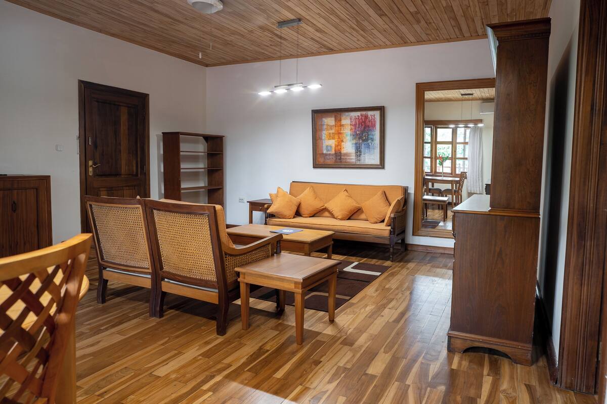 Una sala de estar con piso de madera, un sofá, una mesa de centro, una silla y una estantería.