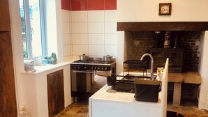 Una cocina con estufa a gas, un fregadero y una chimenea.
