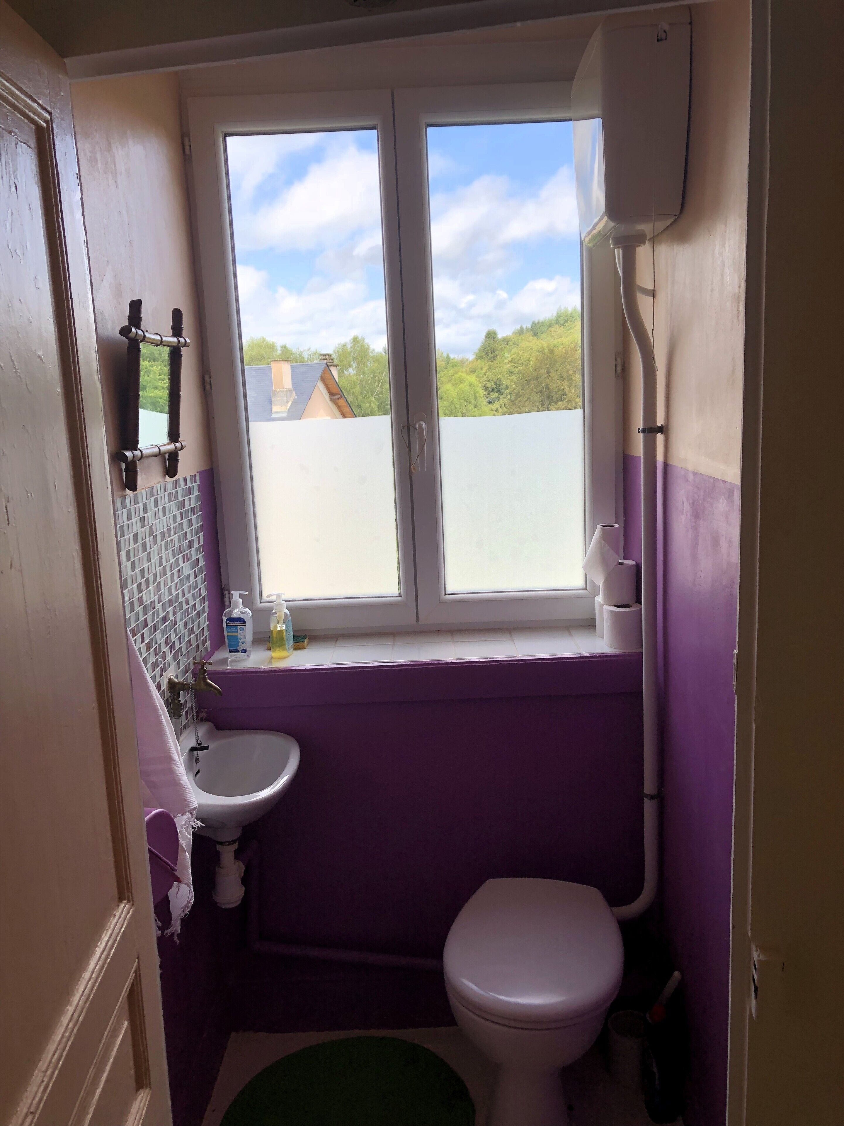 A small bathroom with a window, a sink, and a toilet.