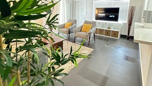 Un salon moderne avec un canapé, une table basse et un téléviseur à écran plat.