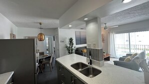 Une cuisine moderne dotée d’un îlot central, d’appareils électroménagers en acier inoxydable et d’un coin repas avec une table et des chaises.
