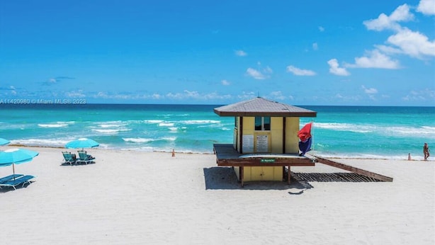 Une plage dotée d’un poste de surveillance pour les sauveteurs, de chaises longues et offrant une vue dégagée sur l’océan.