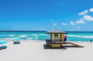A beach with a lifeguard station, sun loungers, and a clear view of the ocean.