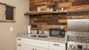 A kitchen with a granite countertop, stainless steel sink, microwave, and gas stove.
