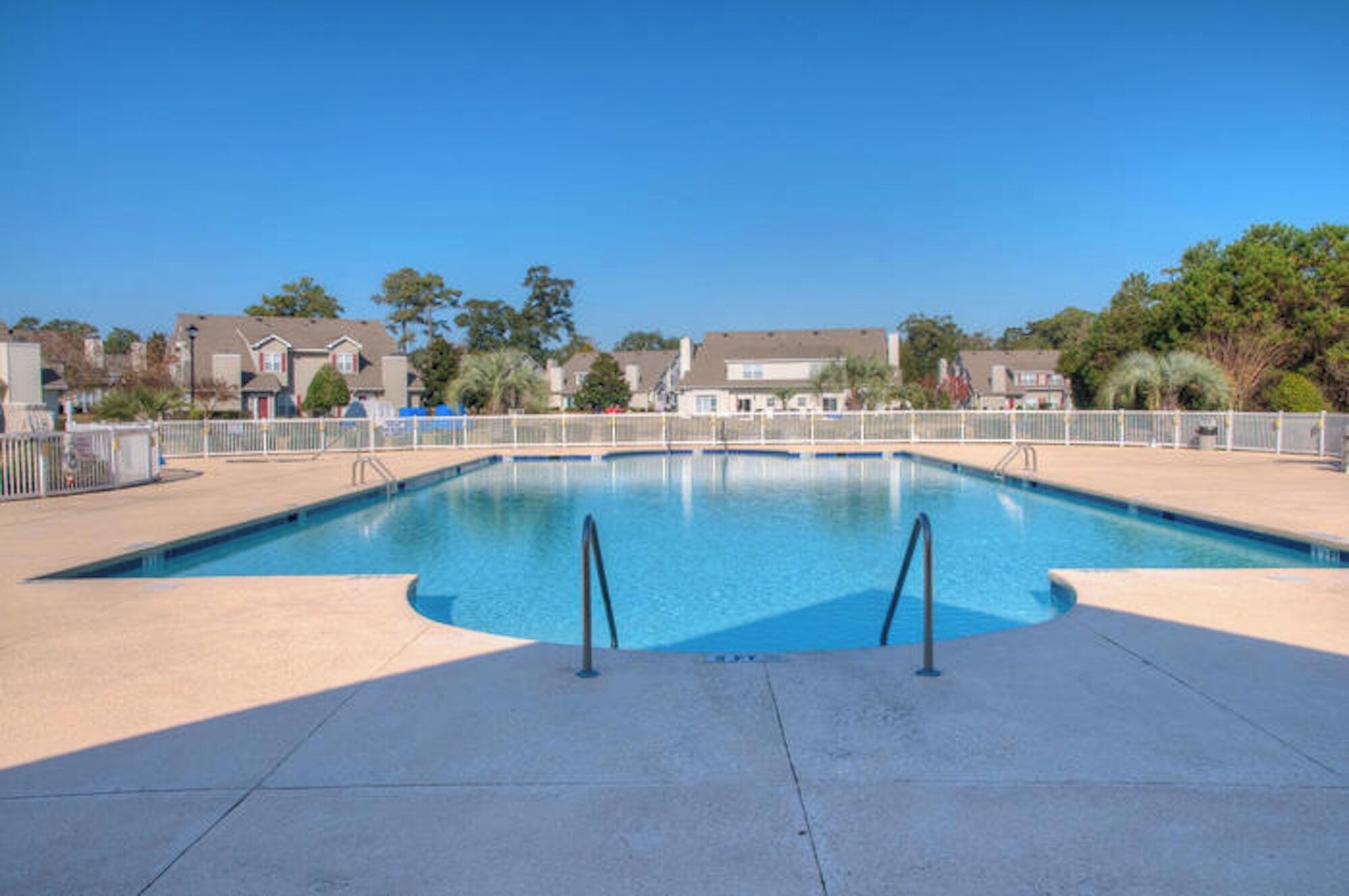 Une piscine rectangulaire à l’eau d’un bleu limpide, entourée d’une terrasse en béton.