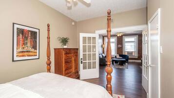 A bedroom with a four-poster bed, a dresser, and a door leading to another room.