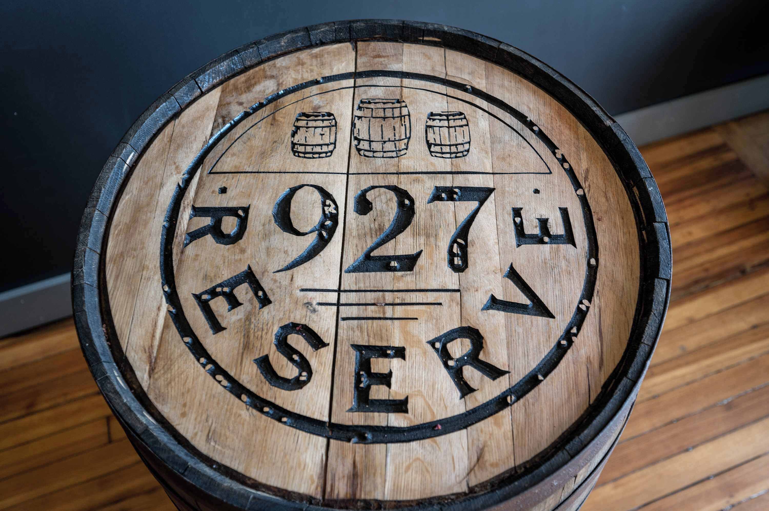 Een houten vat met de opdruk ‘R 927E RESERVE’ en drie vaten erboven.