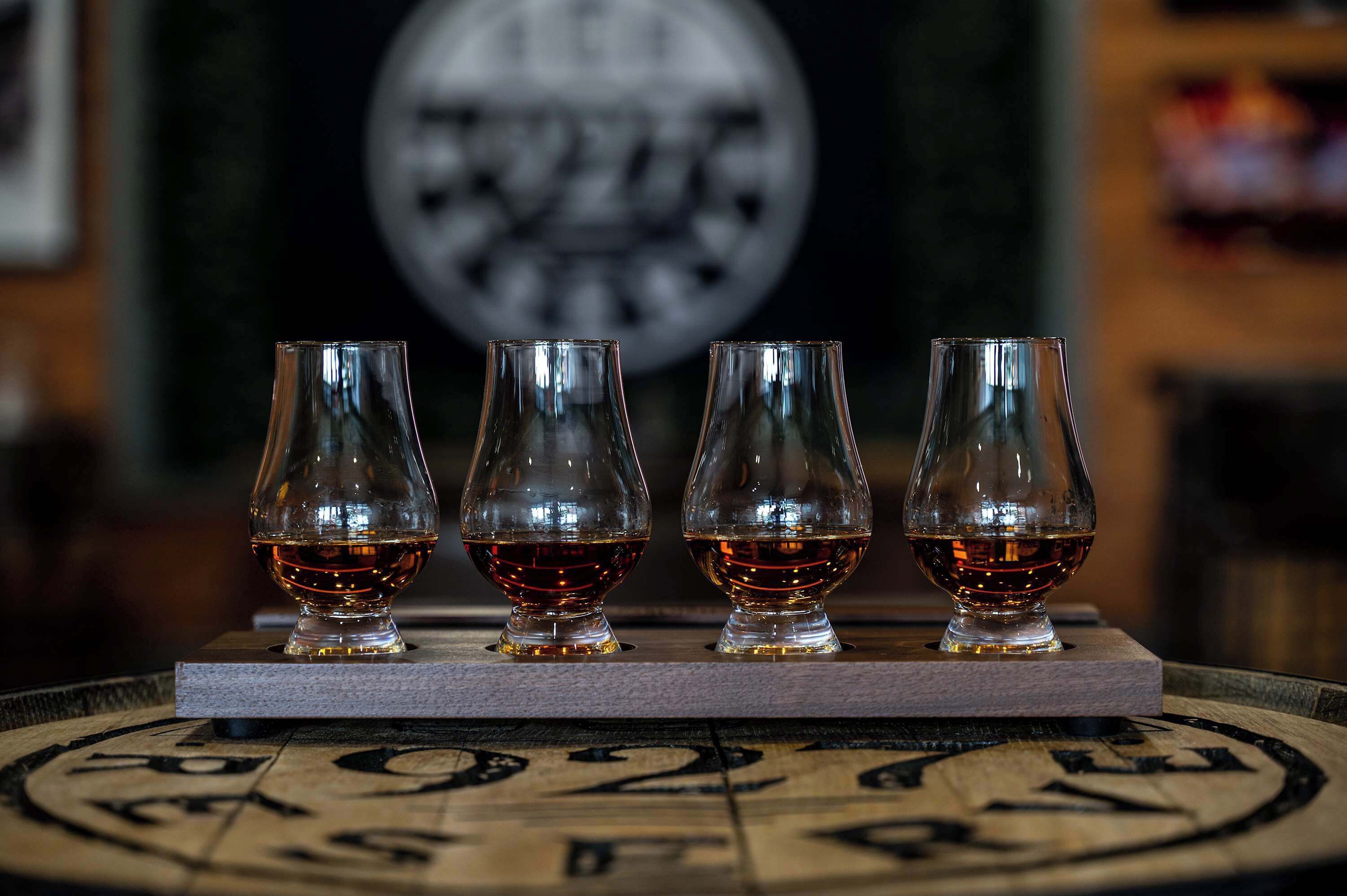 Vier whiskeyglazen op een houten tafel met een rond blad.