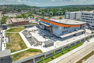 Un edificio grande y moderno con techo curvo y detalles en naranja, identificado como “MegaCorp Pavilion”.