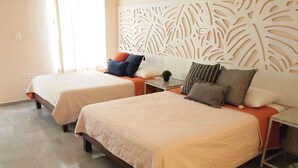 A hotel room with two beds, a decorative wall panel, and a small table with a plant. - Encantadora Suite, en la Mejor Zona de Paseo Montejo. En el Barrio Gastronómico (Mérida)