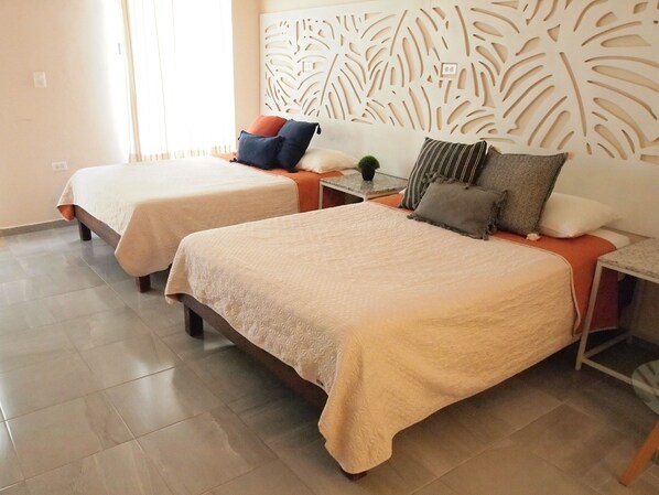 A hotel room with two beds, a decorative wall panel, and a small table with a plant. - Encantadora Suite, en la Mejor Zona de Paseo Montejo. En el Barrio Gastronómico (Mérida)
