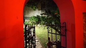 An arched entrance with a metal gate leading to a garden area. - Encantadora Suite, en la Mejor Zona de Paseo Montejo. En el Barrio Gastronómico (Mérida)