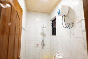 Ein Badezimmer mit Dusche, Toilette und Warmwasserbereiter.