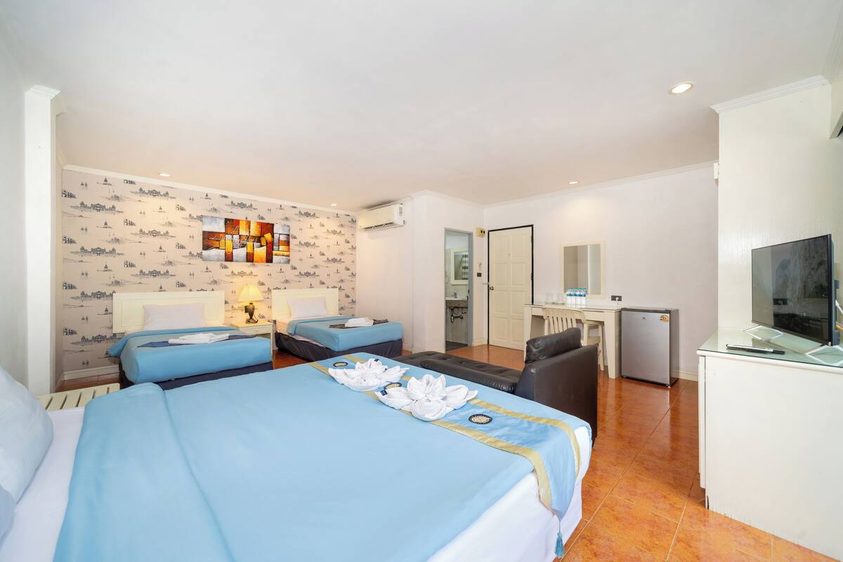 A hotel room with two beds, a desk, a chair, a TV, and a minibar.