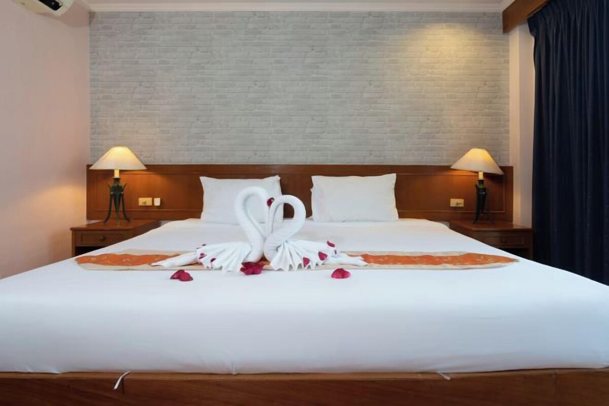 Una habitación de hotel con una cama grande, dos lámparas de noche y una pared con diseño de ladrillo.