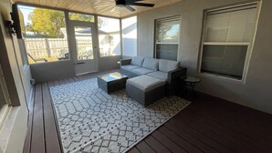 A covered patio area with a ceiling fan, a gray sofa, a small table, and a patterned rug. - Melbourne, FL Home-Away From Home - Eau Gallie District  (Melbourne)
