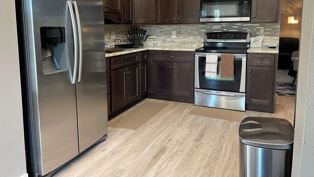 A modern kitchen with dark wood cabinets, stainless steel appliances, and a granite countertop. - Melbourne, FL Home-Away From Home - Eau Gallie District  (Melbourne)