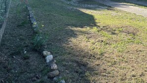 Een rustiek huis met een gevel van natuursteen, een schotelantenne en een kleine tuin met een stenen rand.