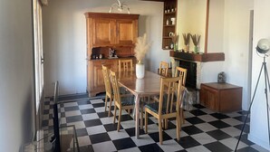 Een eetgedeelte met een geruite vloer, houten stoelen, een tafel en een kroonluchter.