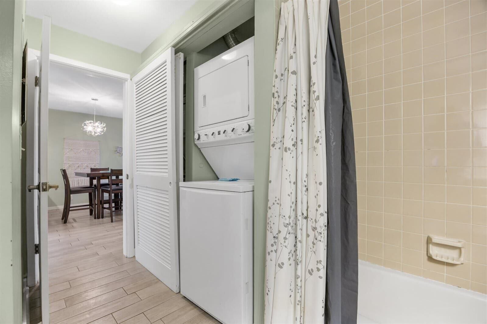 A hallway with a dining area, a white appliance, and a tiled wall.