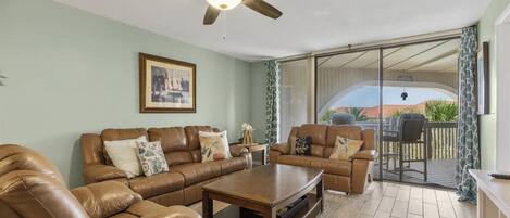 A living room with a brown leather sofa set, a wooden coffee table, and a ceiling fan.