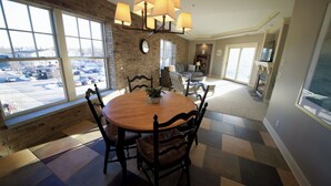 A dining area with a brick wall, large windows, and a chandelier. - Luxury condo in the heart of downtown Grand Haven. (Grand Haven)