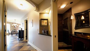 A hallway with a checkered floor, a dining area with a table and chairs, and a kitchen with a sink and pendant lights. - Luxury condo in the heart of downtown Grand Haven. (Grand Haven)